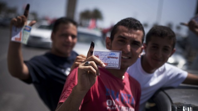 Libyan men hold their elections ID cards while celebrating election day in Tripoli on July 7, 2012. (photo credit: Manu Brabo/AP)